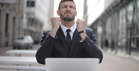 man in black suit sitting on chair beside buildings