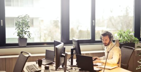 man with headphones facing computer monitor